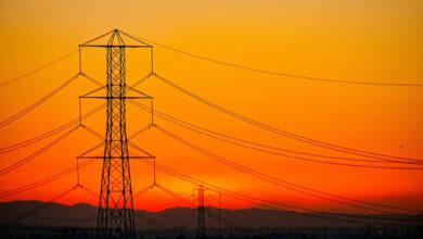 a transmission tower in front of an orange California sunset